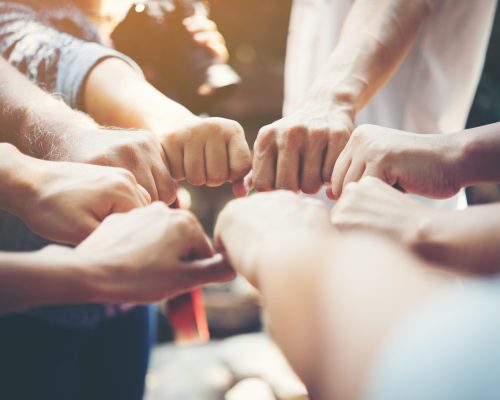 Close up of young people putting their hands together. Team with stack of hands showing unity and teamwork.
